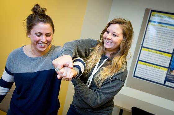 Photo of two young Chatham University students demonstrating physical therapy techniques.